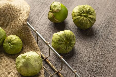 fresh tomatillos on brown wood background in a wire basket with burlapの写真素材