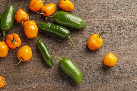 fresh jalapeno and habanero peppers on a wood backgroundの写真素材