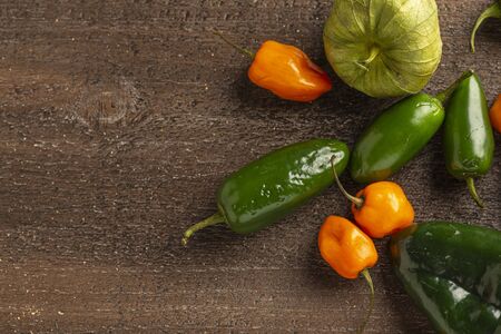 fresh tomatillos, poblano, jalapeno and habanero peppers on a wood background, overheadの写真素材