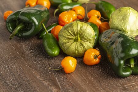 fresh tomatillos, poblano, jalapeno and habanero peppers on a wood backgroundの写真素材