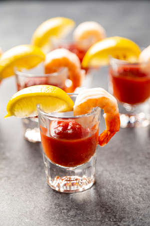 shrimp cocktail appetizers in shot glasses with lemon wedgesの写真素材