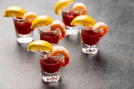 shrimp cocktail appetizers in shot glasses with lemon wedgesの写真素材