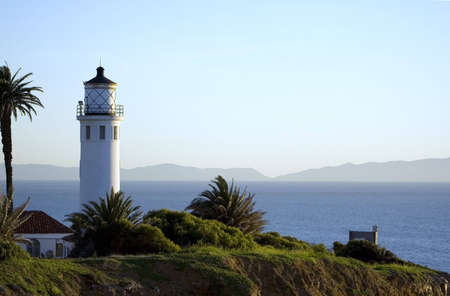 lighthouse on a cliff overlooking the ocean and mountains in the distanceの写真素材