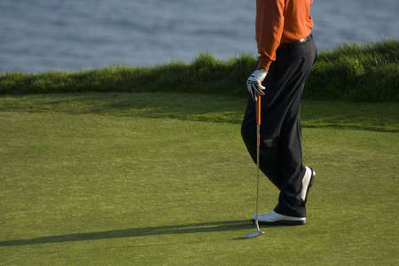golfer waits on green to make putt with ocean in the backgroundの写真素材