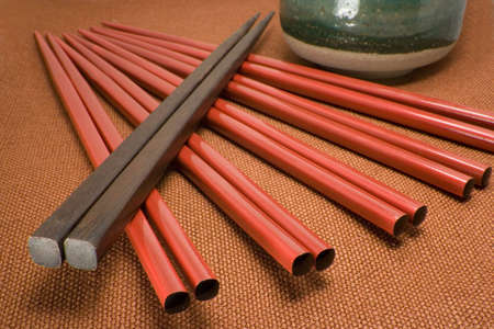 red and brown chopsticks arranged diagonally leading to tea cupの写真素材