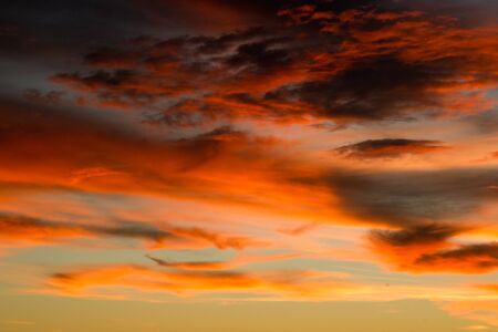 Sky filled with dark and light orange colored clouds during sunset.の写真素材