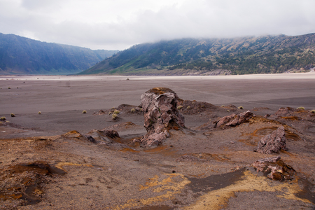 Sand sea with mountains at the background and a clouded sky in the morning at the Tengger Semeru National Park in East Java, Indonesia.の写真素材