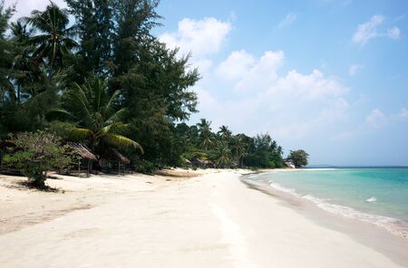 Tropical stretched out white sand beach and palm trees with blue colored ocean seashore water in the afternoon at Tanjung Pinang on Bintan island, Indonesia.のeditorial素材