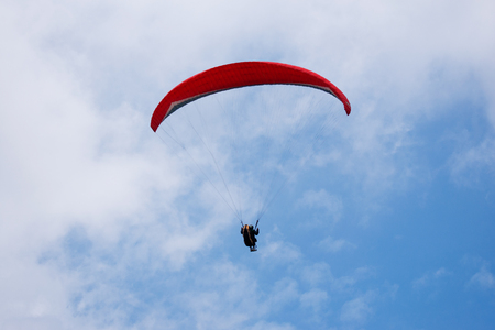 One paraglider in the blue sky with red parachute gliding for fun and excitement towards the ground.の写真素材