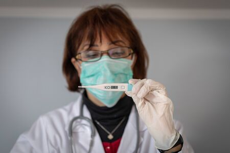 Young female doctor detecting the temperature of a Covid-19 patientの写真素材