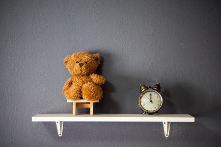 Retro alarm clock and teddy bear with gray wall backgroundの写真素材