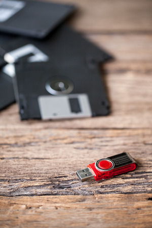 USB storage drive and floppy disks on a wooden tableの写真素材
