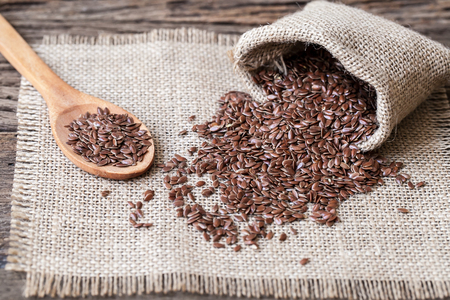 Flax seeds in the sack on wooden backgroundの写真素材