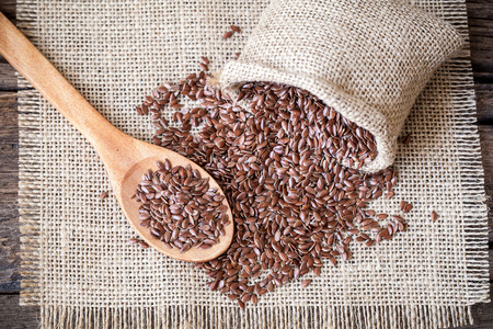 Flax seeds in the sack on wooden backgroundの写真素材