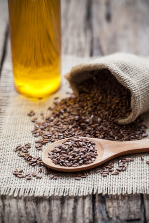 Flax seeds in the sack and oli on wooden backgroundの写真素材