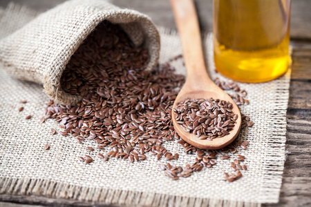 Flax seeds in the sack and oli on wooden backgroundの写真素材