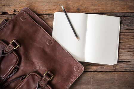 blank notebook with leather bag on wooden tableの写真素材