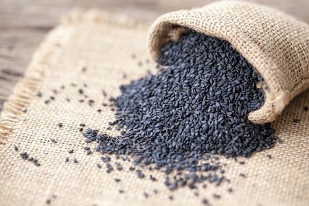 black sesame seeds on sack cloth and wooden backgroundの写真素材