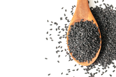 black sesame seeds in wooden spoon on white backgroundの写真素材