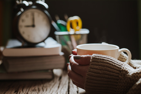 Close up of woman's hands holding a coffee mug, vintage color toneの写真素材