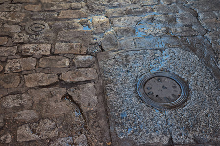 Close up of wet old stone floor with puddles and water supply coversの写真素材