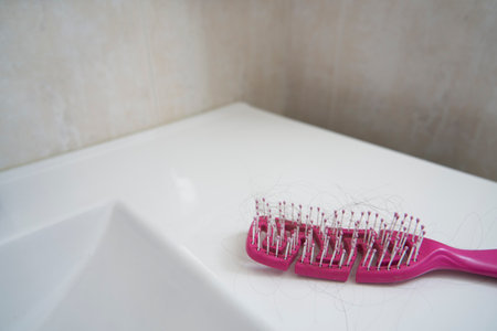 Pink comb with tangled hairs due to a hair loss problem in a washbasinの写真素材