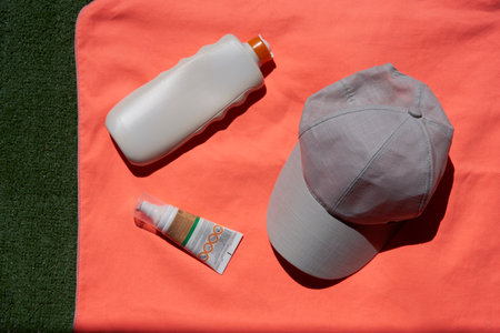 Close-up of a bottle of sunscreen and a cap on an orange towelの写真素材
