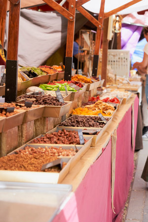 A bustling medieval market stall filled with a colorful assortment of dried fruits and nuts, inviting customers into a world of flavorsの写真素材