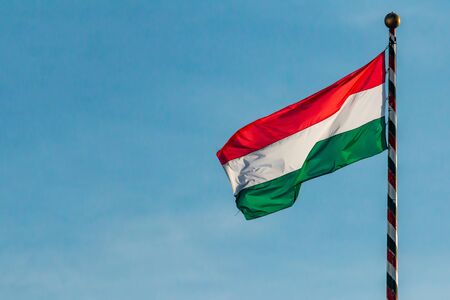 Hungary, Hungarian national flag waving on blue sky backgroundの写真素材