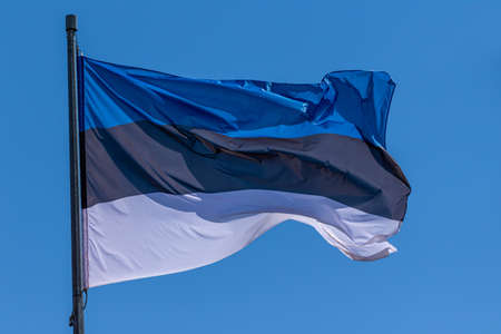 Estonian national flag waving on blue sky background. Republic of Estonia, EEの写真素材