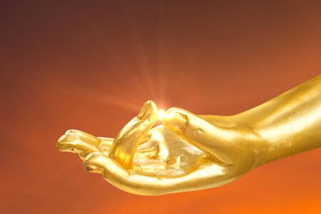 Golden hand of buddha statue with lens flare at fingerの写真素材