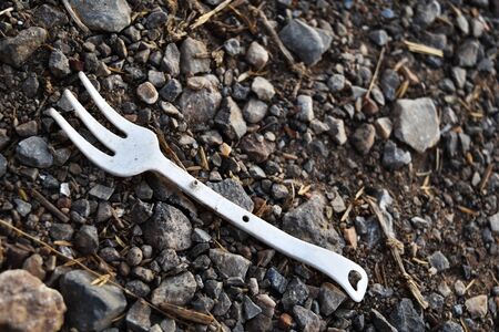 Detail dirty white plastic fork on dirty rounh groundの写真素材