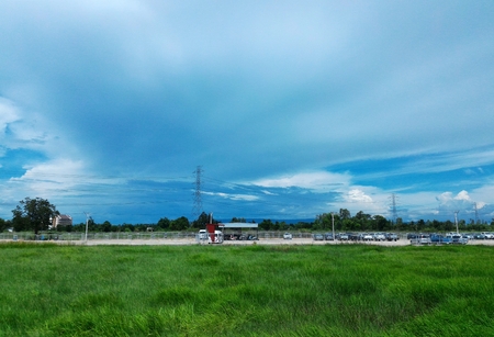 car park beside green rice field under cloudy blue skyの写真素材