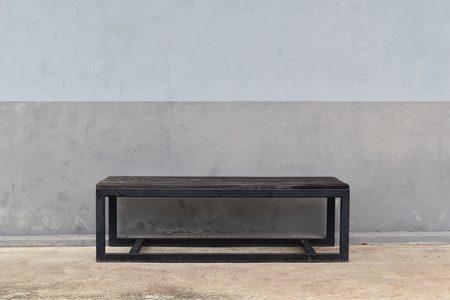 steel long bench in front of dirty gray old wallの写真素材