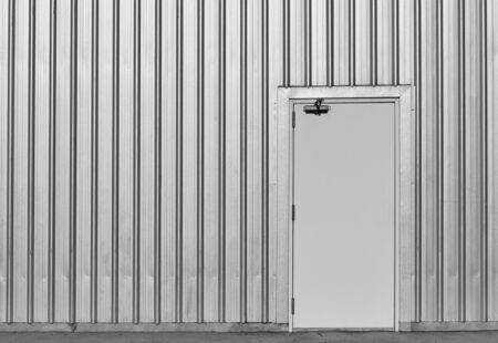 white door in old and dirty metal wall  on dirty concrete for backgroundの写真素材