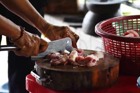 cutting pork by knife on wood chopping board prepare cook for party.の写真素材
