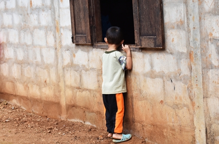 little boy look in window on dirty wall in countrysideの写真素材