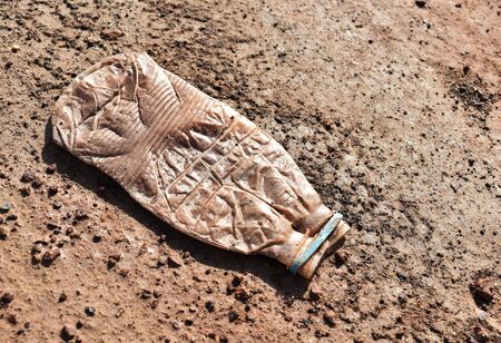 flat dirty plastic bottle on dry soil groundの写真素材