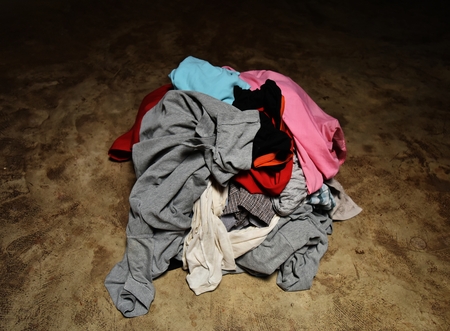 pile of dirty clothes in green basket on cement ground