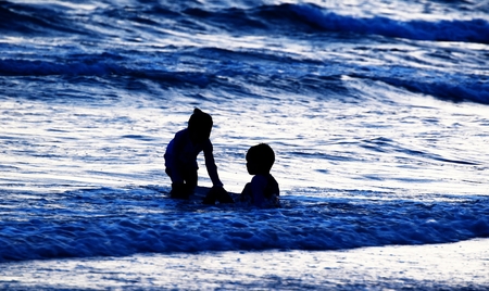 silhouette of kid on beach and in sea in evening before sunset in holidayの写真素材