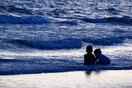 silhouette of kid on beach and in sea in evening before sunset in holidayの写真素材
