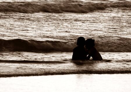 silhouette of kid on beach and in sea in evening before sunset in holidayの写真素材
