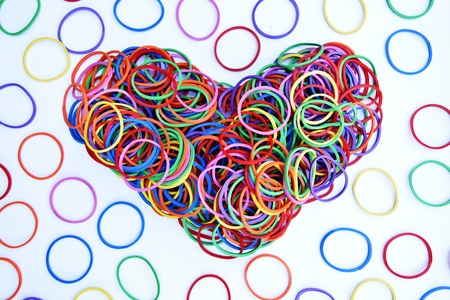 heart shape of colorful rubber ring on white paper background