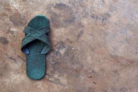 old green rubber shoe on dirty cement ground for backgroundの写真素材
