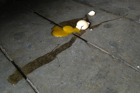 broken raw egg on dirty concrete groundの写真素材