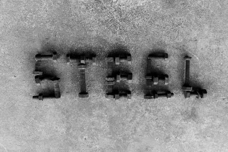 letter word is steel by old and rusty nut on dirty groundの写真素材