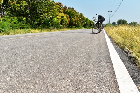 old and dirty white line on old asphalt and brown grass in countryside in selective focus for backgrounの写真素材