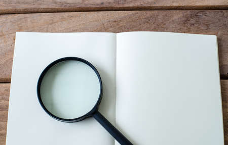 Magnifying Glass and notebook on wood background.の写真素材