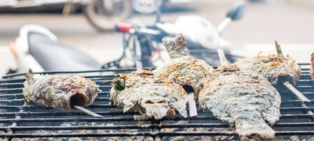 Salt Crusted Grilled Nile Tilapia Fish on Grate on charcoal stoveの写真素材