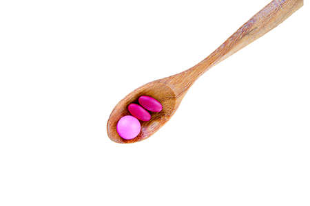Pills on spoon on white background